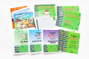 The components of the Building On Patterns Kindergarten, Second Edition Student Kit on a white background, including a stack of print storybooks, their BOP braille companions, a coloring book, a parent booklet, and three binders.
