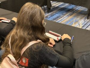 A seated student wearing a backpack uses a Cranmer abacus.